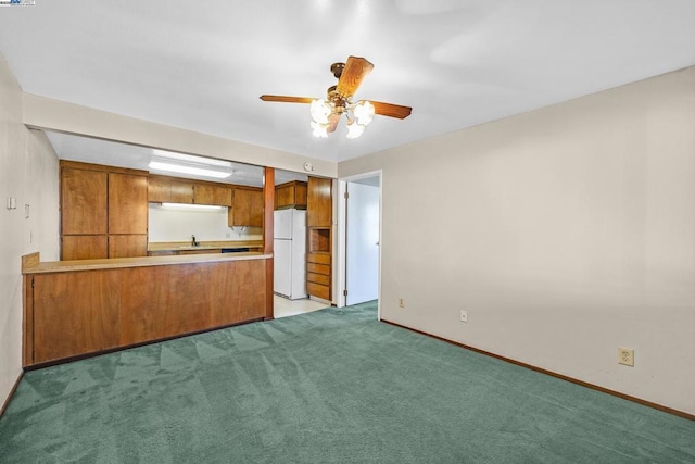 kitchen with sink, light colored carpet, kitchen peninsula, white fridge, and ceiling fan