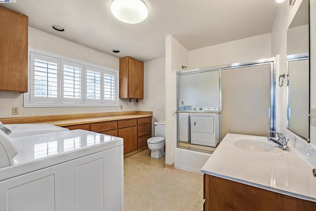 full bathroom with separate washer and dryer, vanity, enclosed tub / shower combo, and toilet