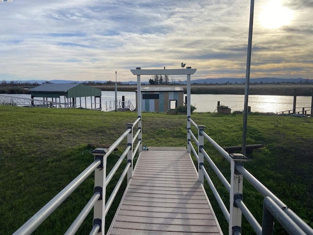 view of dock with a water view and a lawn