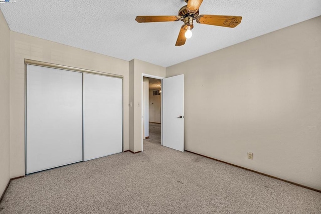 unfurnished bedroom with ceiling fan, light colored carpet, a textured ceiling, and a closet