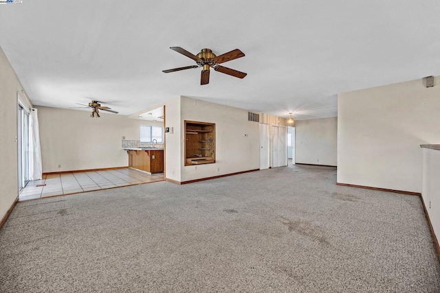 unfurnished living room featuring sink, light colored carpet, and ceiling fan