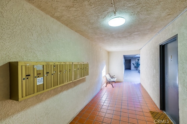 hall featuring a mail area, tile patterned floors, and a textured ceiling