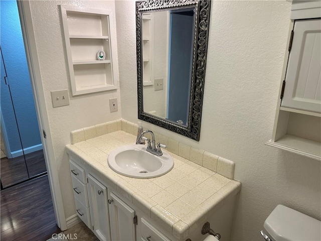 bathroom featuring vanity, toilet, wood-type flooring, and built in features