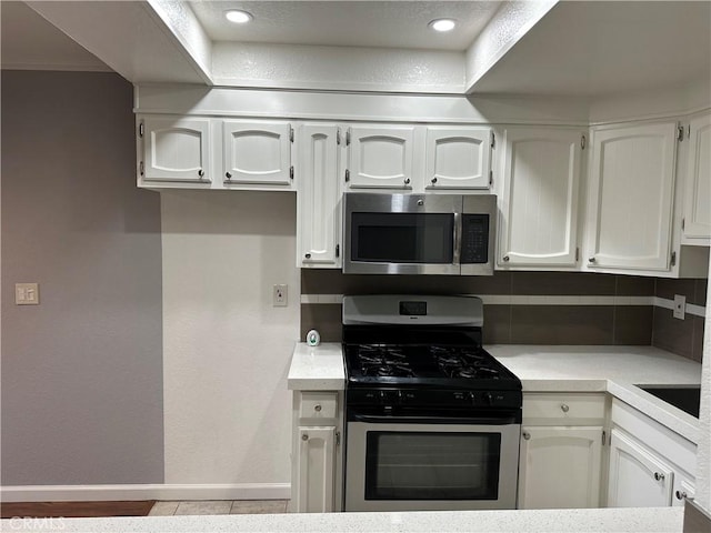 kitchen with stainless steel appliances, decorative backsplash, and white cabinets