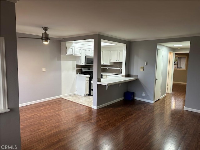 kitchen featuring a kitchen bar, white cabinetry, dark hardwood / wood-style flooring, kitchen peninsula, and stainless steel appliances