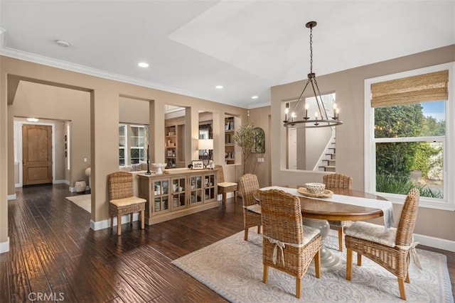 dining space featuring built in shelves, dark hardwood / wood-style flooring, ornamental molding, and a chandelier