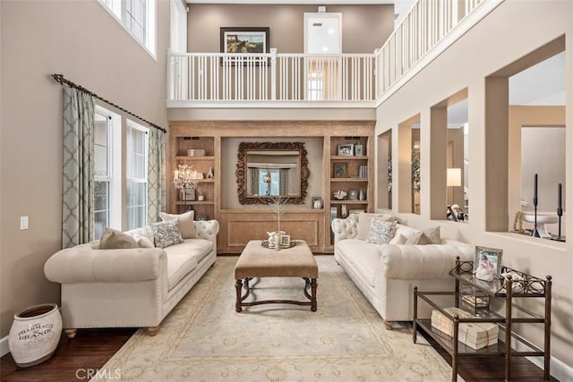 living room featuring wood-type flooring, built in features, and a towering ceiling