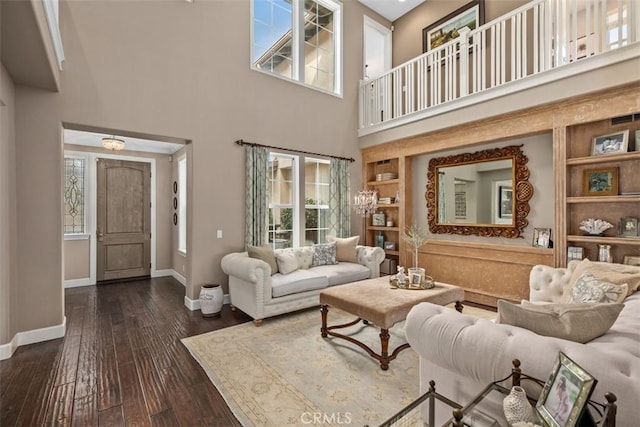 living room with built in shelves, dark hardwood / wood-style floors, a wealth of natural light, and a towering ceiling