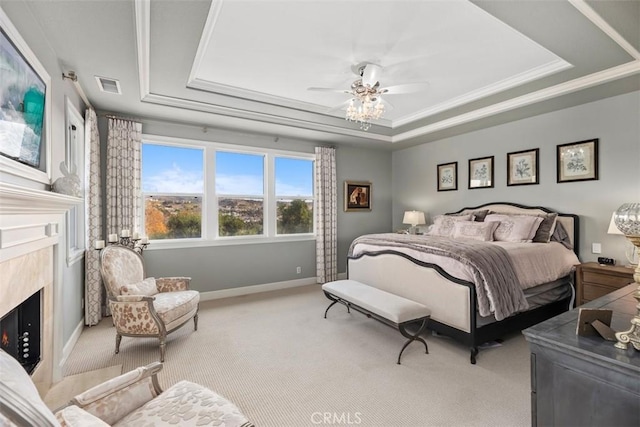 carpeted bedroom featuring ceiling fan, ornamental molding, a raised ceiling, and a premium fireplace