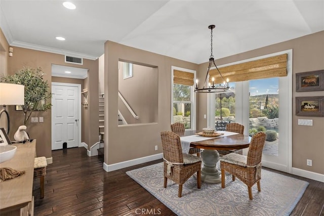 dining space with dark hardwood / wood-style floors, crown molding, and a chandelier