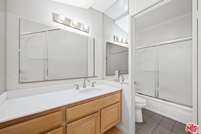 full bathroom featuring shower / bath combination with glass door, tile patterned flooring, toilet, and vanity