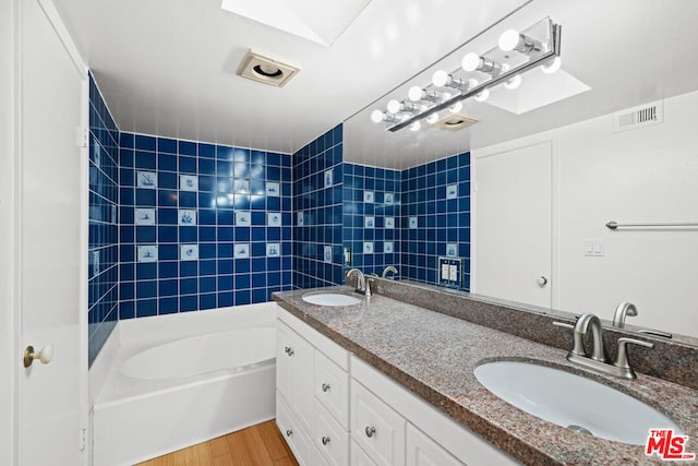 bathroom featuring a skylight, hardwood / wood-style floors, vanity, and tiled shower / bath