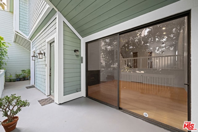 exterior space with wood walls, vaulted ceiling, and concrete flooring