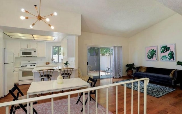 interior space with white appliances, white cabinetry, dark hardwood / wood-style floors, a chandelier, and vaulted ceiling