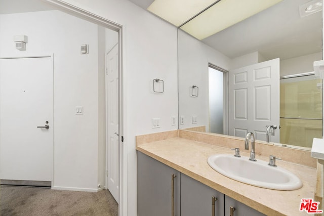 bathroom featuring a shower with door and vanity