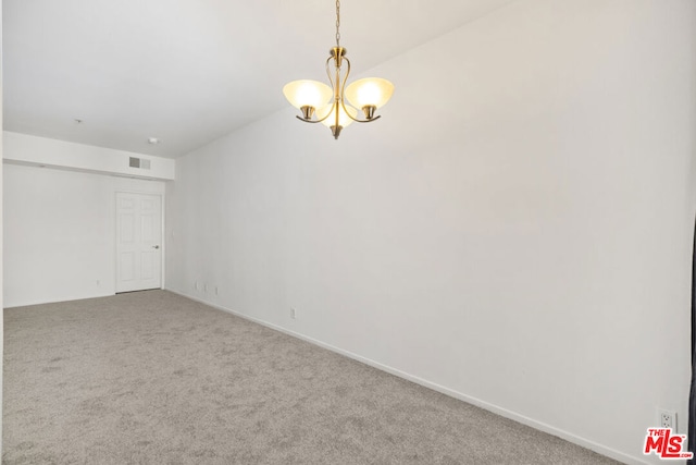 unfurnished room featuring a chandelier and carpet floors