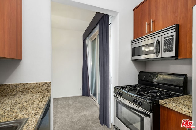 kitchen featuring sink, light stone countertops, appliances with stainless steel finishes, and light carpet