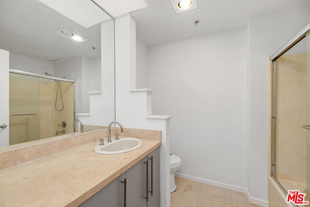 full bathroom featuring toilet, bath / shower combo with glass door, tile patterned floors, and vanity