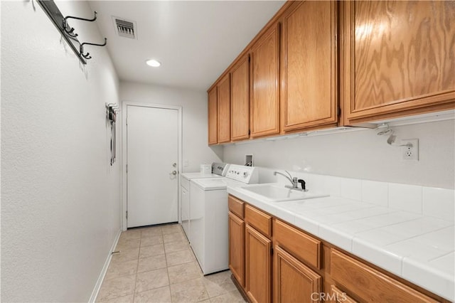 laundry area featuring cabinets, light tile patterned floors, separate washer and dryer, and sink