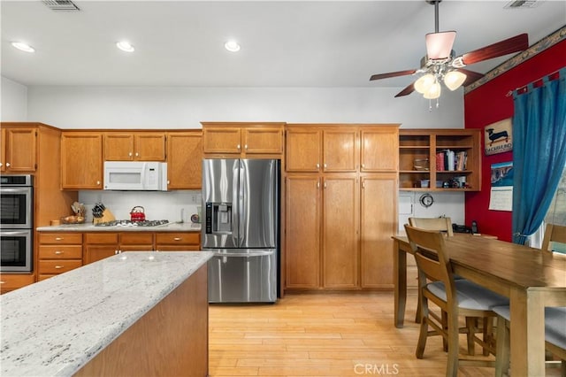 kitchen featuring ceiling fan, light hardwood / wood-style floors, hanging light fixtures, light stone countertops, and stainless steel appliances