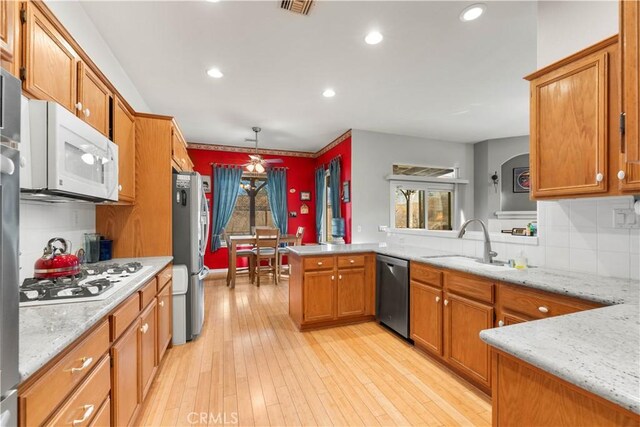 kitchen with backsplash, pendant lighting, kitchen peninsula, sink, and stainless steel appliances