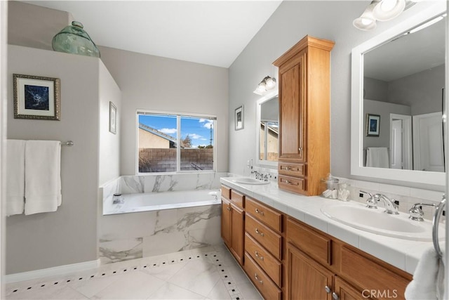 bathroom with tiled tub, vanity, and tile patterned flooring