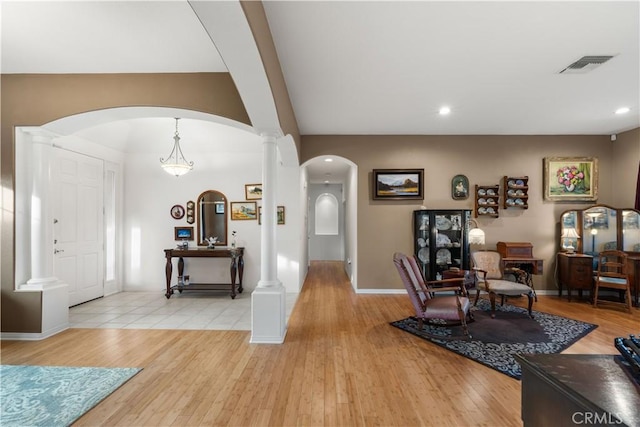 foyer entrance with ornate columns and light wood-type flooring