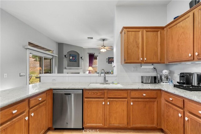 kitchen with sink, kitchen peninsula, ceiling fan, light stone counters, and stainless steel dishwasher