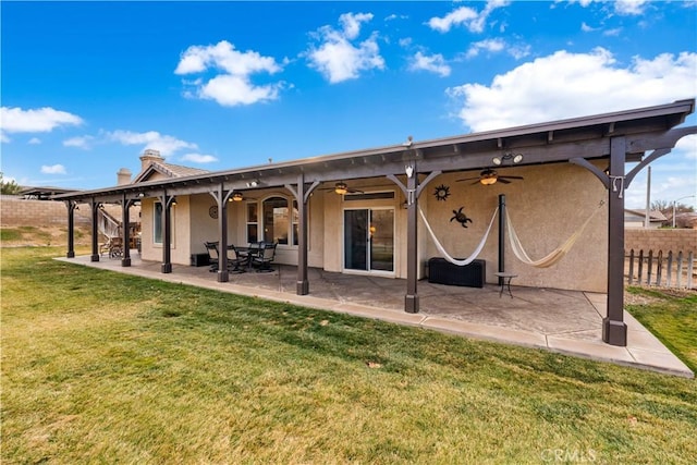 back of house with ceiling fan, a lawn, and a patio