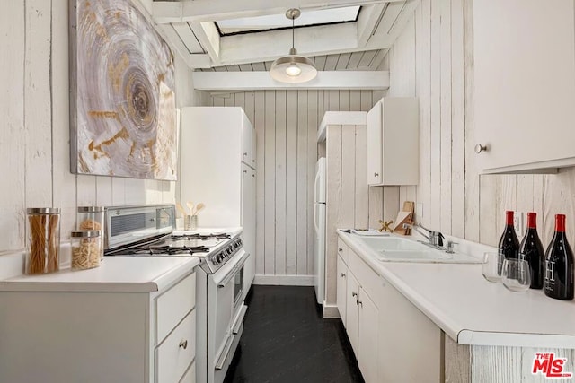 kitchen with white appliances, white cabinets, decorative light fixtures, wooden walls, and beam ceiling