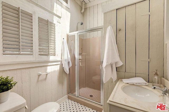 bathroom featuring an enclosed shower, vanity, toilet, and wood walls