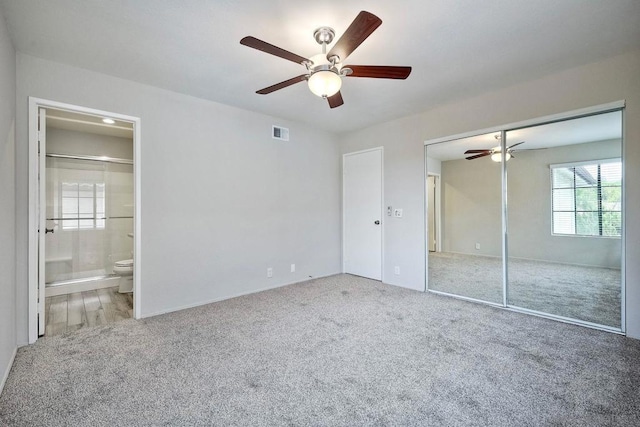 unfurnished bedroom featuring ceiling fan, ensuite bathroom, a closet, and carpet floors