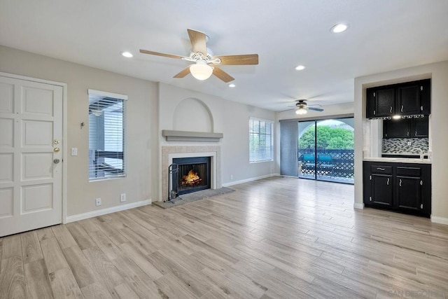 unfurnished living room with ceiling fan, light hardwood / wood-style flooring, and a tile fireplace