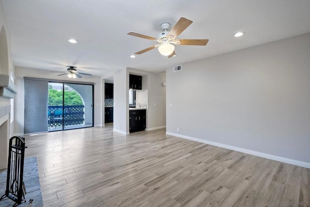 unfurnished living room featuring ceiling fan and light wood-type flooring