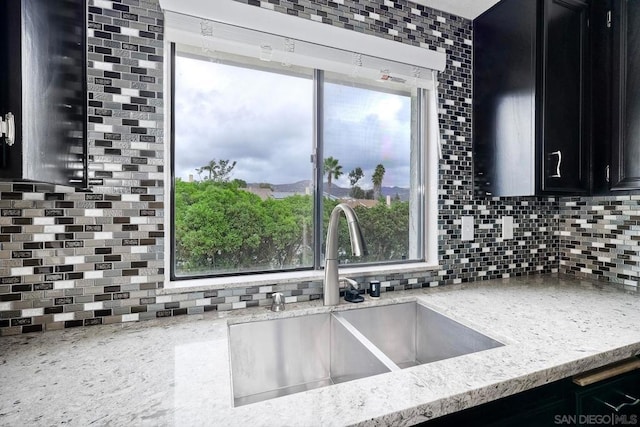 kitchen with backsplash, light stone countertops, and sink