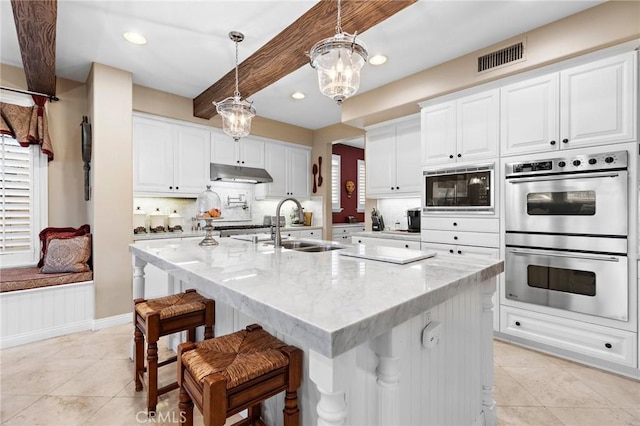 kitchen featuring double oven, black microwave, white cabinetry, hanging light fixtures, and light stone countertops