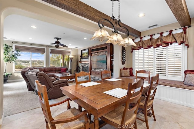 tiled dining room with beamed ceiling and ceiling fan with notable chandelier