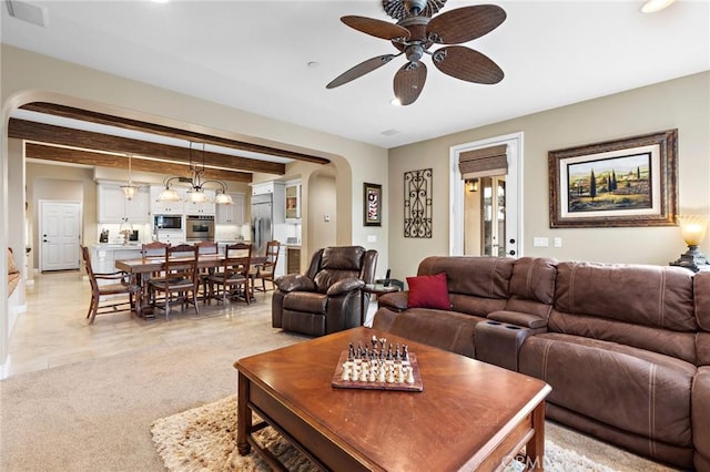 carpeted living room featuring ceiling fan and beamed ceiling