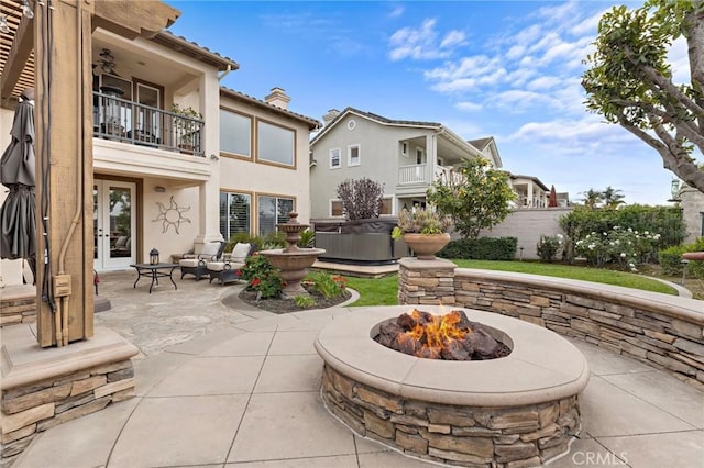 view of patio featuring a balcony and an outdoor fire pit