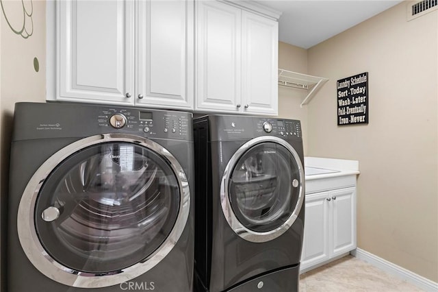 clothes washing area with cabinets, light tile patterned flooring, and independent washer and dryer