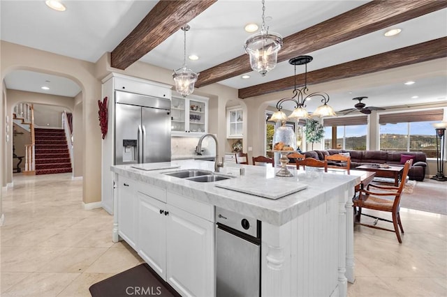 kitchen featuring built in fridge, white cabinetry, sink, and a kitchen island with sink