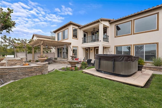 rear view of property featuring a patio, a balcony, a lawn, a pergola, and a hot tub