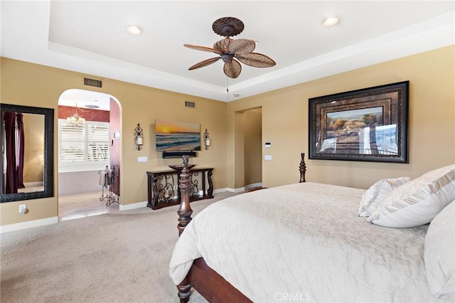 carpeted bedroom featuring ceiling fan and a tray ceiling