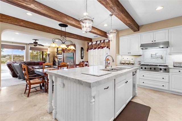 kitchen with a kitchen island with sink, white cabinetry, decorative light fixtures, and stainless steel gas cooktop