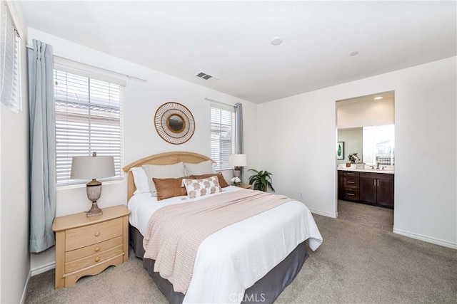 bedroom with sink, ensuite bathroom, and light carpet