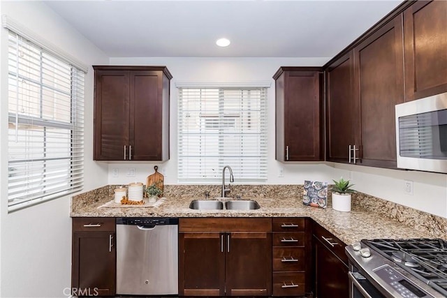 kitchen featuring a healthy amount of sunlight, light stone countertops, sink, and stainless steel appliances