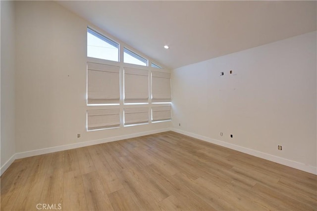 unfurnished room featuring vaulted ceiling and light hardwood / wood-style floors