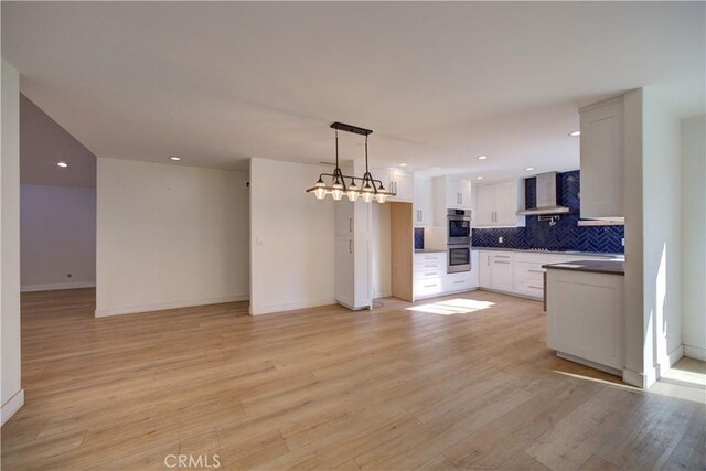 kitchen featuring white cabinetry, light hardwood / wood-style floors, backsplash, and wall chimney range hood