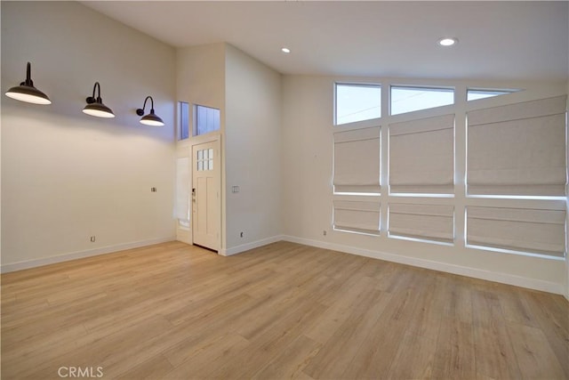 spare room with light wood-type flooring and lofted ceiling