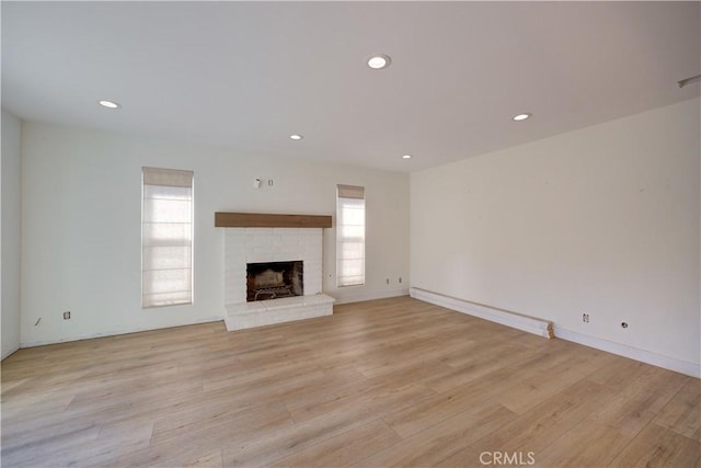 unfurnished living room featuring a brick fireplace and light hardwood / wood-style flooring